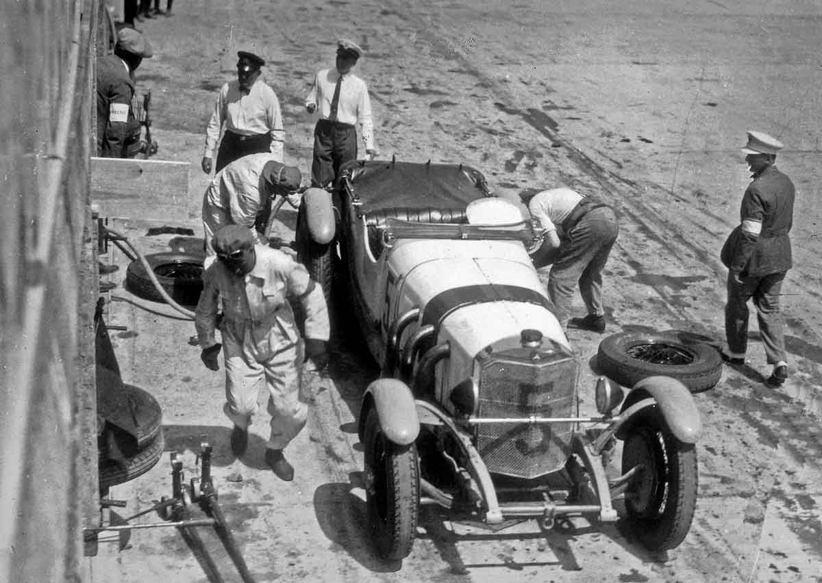 Großer Preis von Deutschland 1928 auf dem Nürburgring, 15. Juli 1928: Reifenwechsel am Mercedes-Benz SS Rennsport-Tourenwagen mit der Startnummer 5 von Otto Merz. Gut zu erkennen sind das schwarze Band über der Motorhaube (Markierung für Fahrzeuge der Gruppe 1 über drei Liter Hubraum) sowie die Abdeckung der hinteren Sitzbank mit einer Persenning. Insgesamt belegt Mercedes-Benz mit dem Typ SS Rennsport-Tourenwagen die ersten drei Plätze.